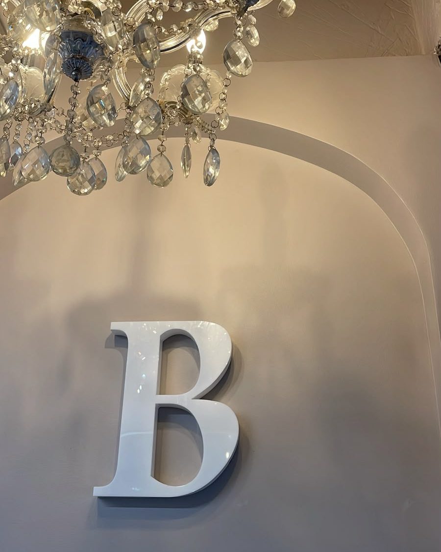 Letra B de Botánica bajo una lámpara de cristal en el salón